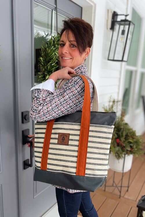 Rogue life maine striped canvas tote bag with clay brown straps on a porch.